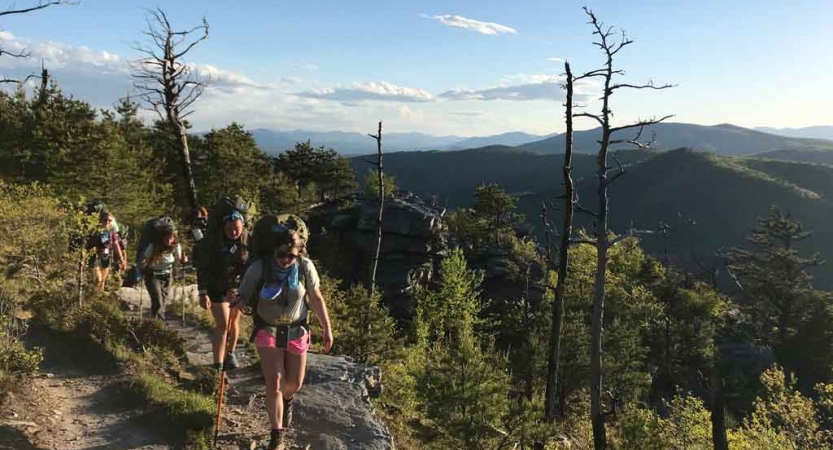 A group of backpackers hike along a trail at high elevation. 